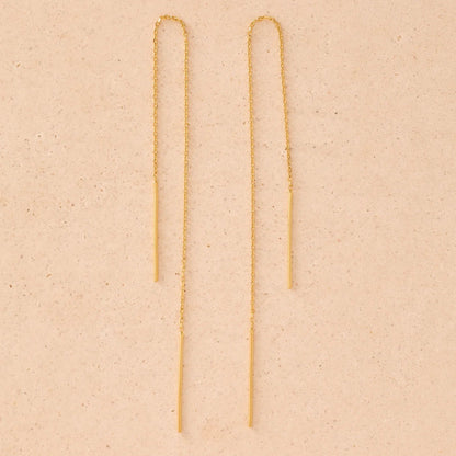 Gold chain earrings on a beige background