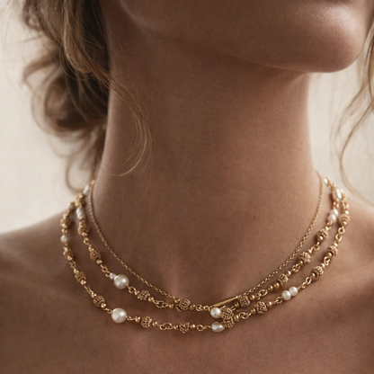 close up of a womans neck with doubled up necklace in gold and pearl