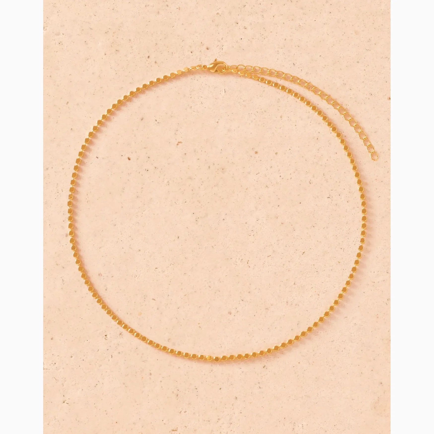 Gold necklace on a beige background
