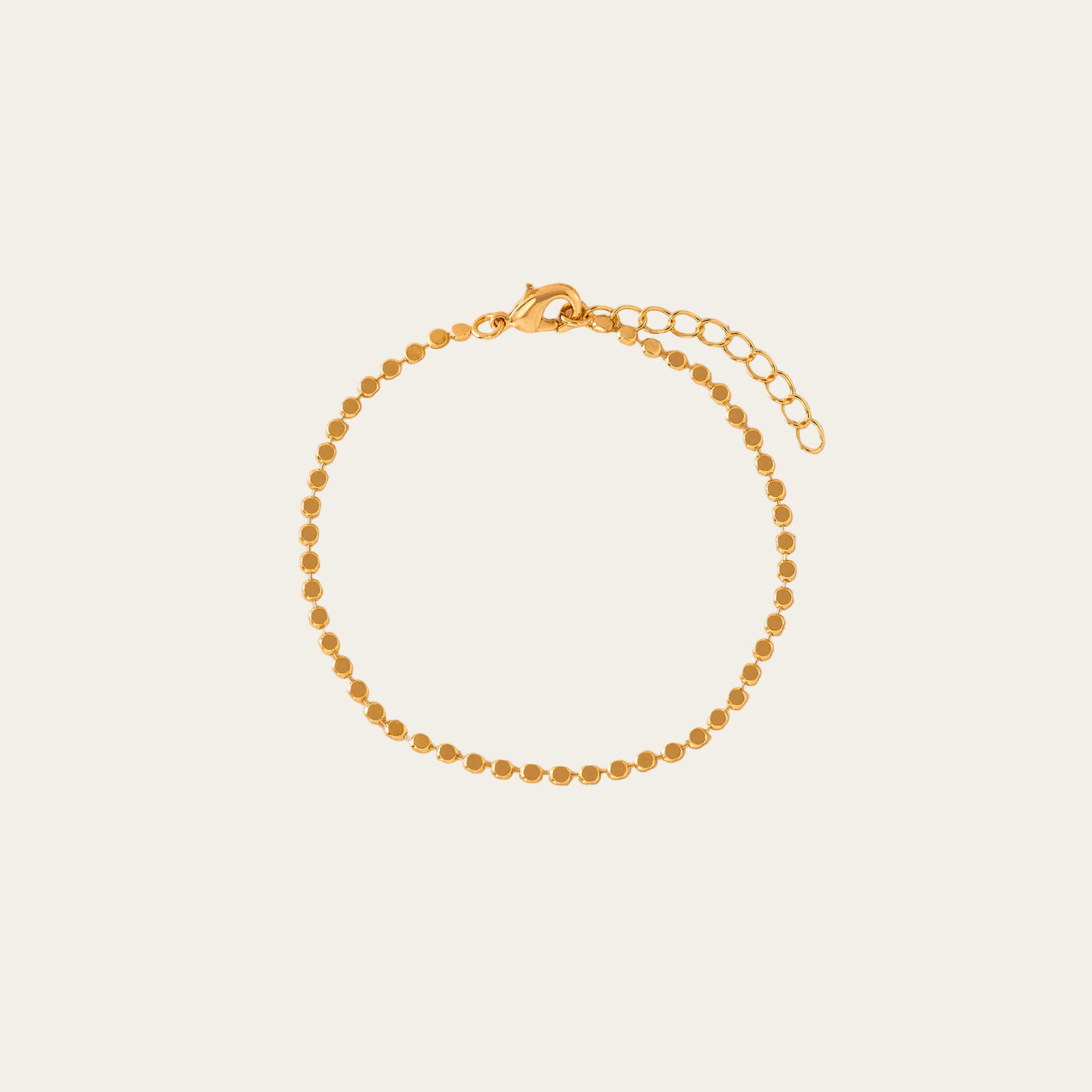 Gold beaded bracelet on a beige background