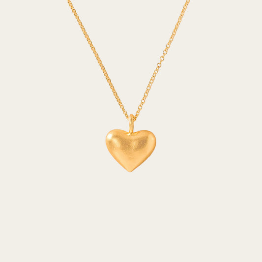 Gold heart-shaped pendant necklace on a beige background