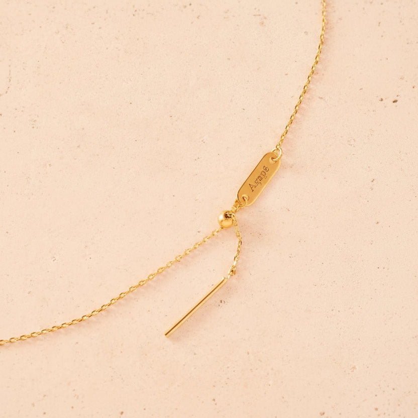 Gold necklace with a tag on a beige background
