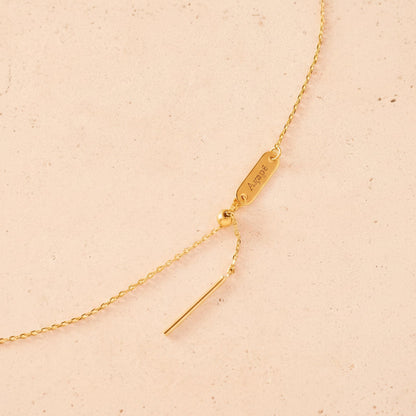 Gold necklace with a tag on a beige background