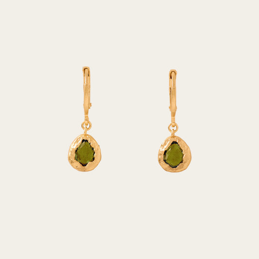 Gold earrings with green stones on a beige background