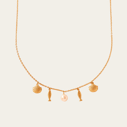 Gold necklace with shell and fish charms on a beige background