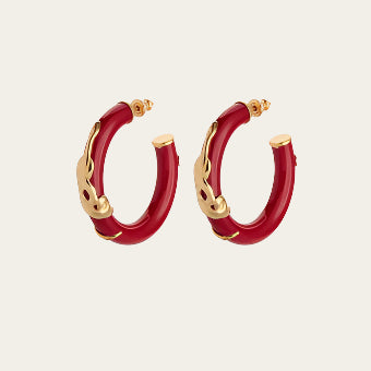 Red hoop earrings with gold snake wrap,  styled on neutral surface