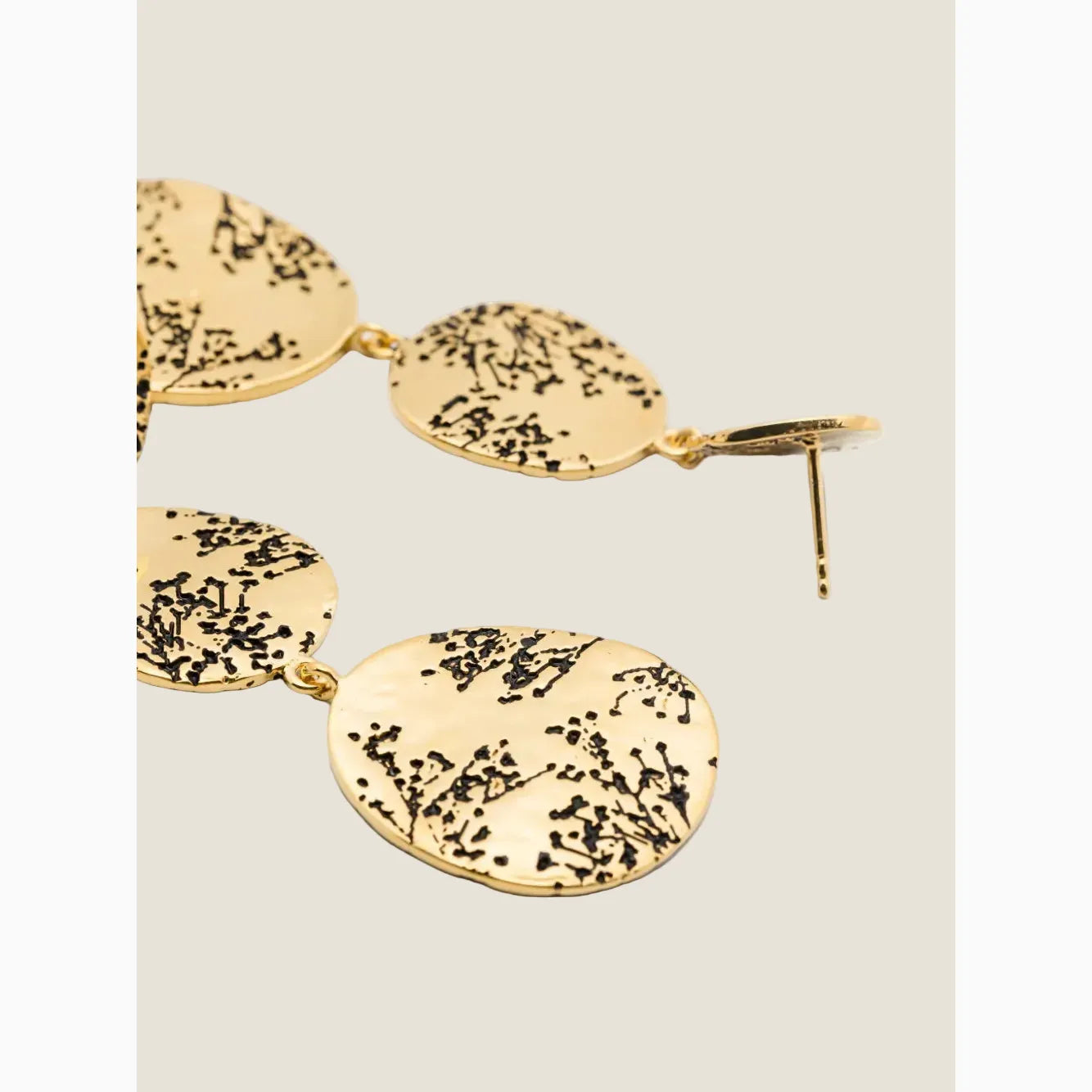 Gold earrings with black branch design on a white background