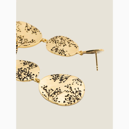 Gold earrings with black branch design on a white background