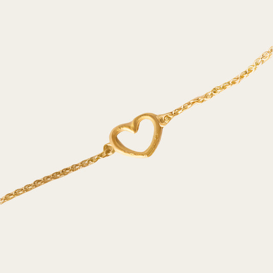 Gold plated chain bracelet with love heart on neutral background
