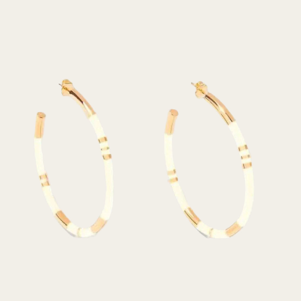 Aurélie Bidermann Positano earrings, featuring ivory-colored stripes in resin and gilded with 750/1000 yellow gold. On flat lay neutral