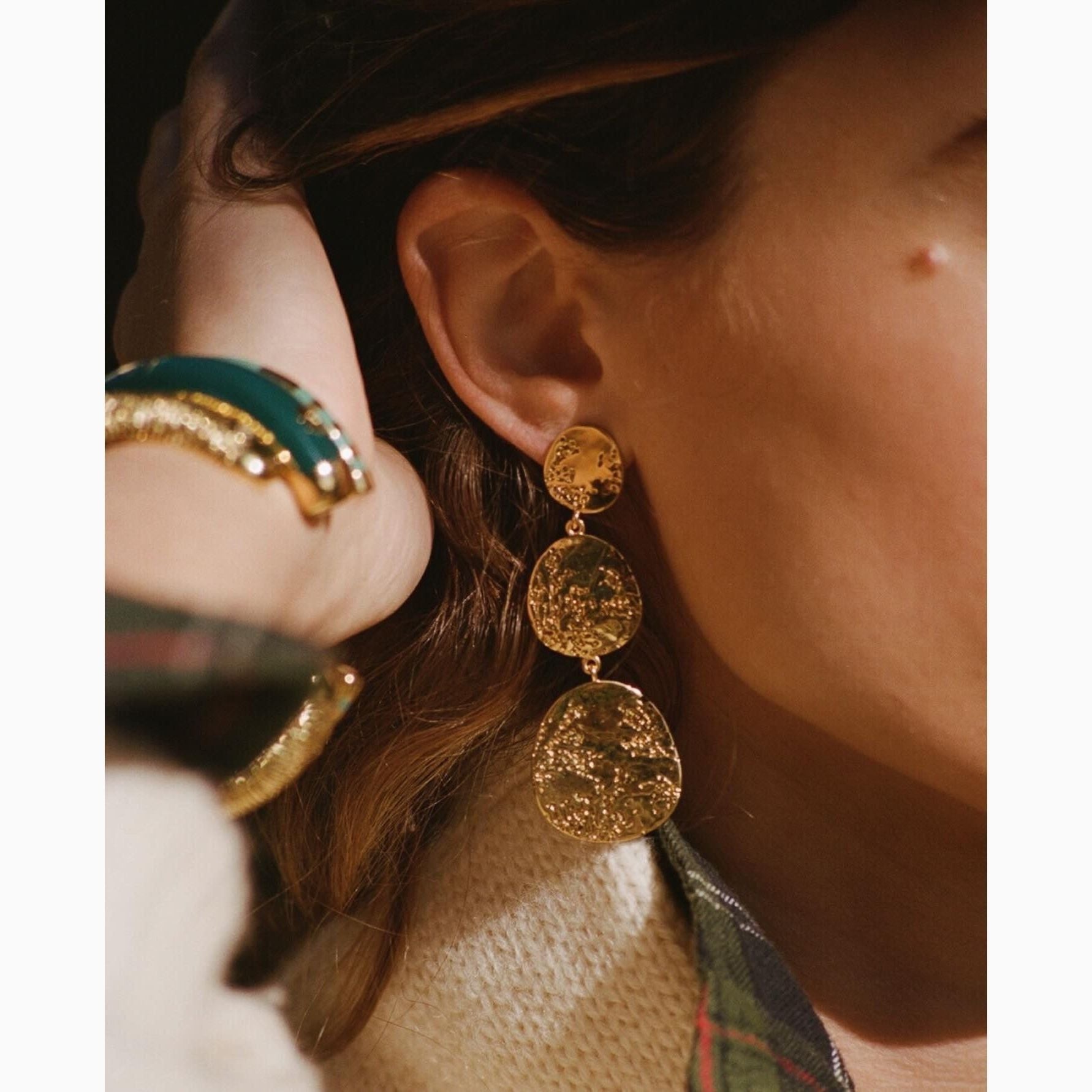 Close up of 3 tier gold earrings on a woman