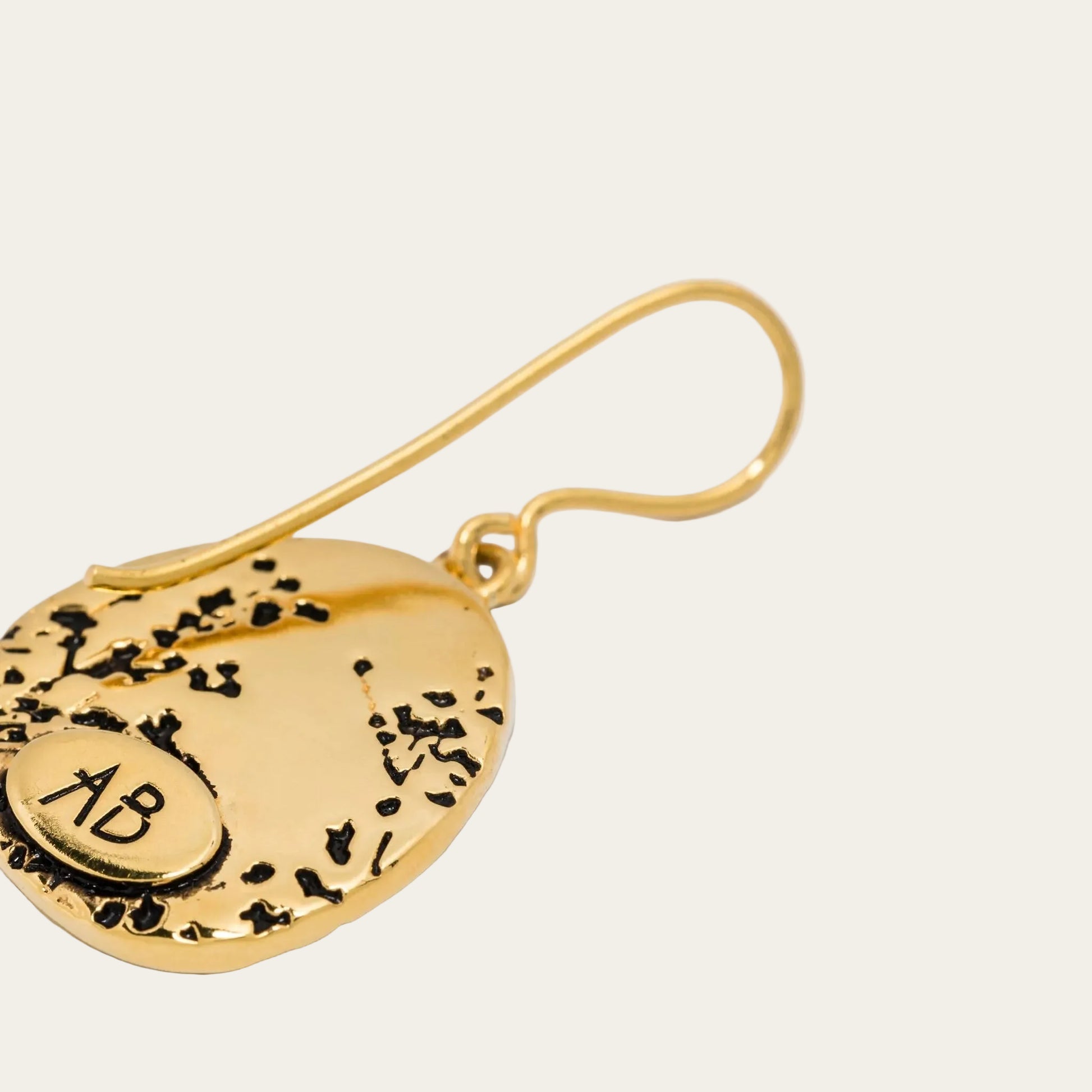 Gold earring with engraved design on a white background