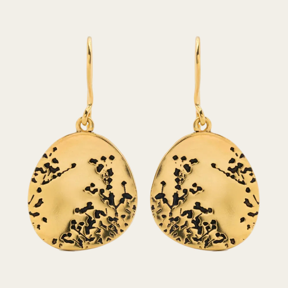 Gold earrings with black floral patterns on a white background