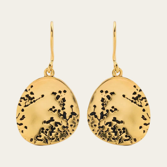Gold earrings with black floral patterns on a white background
