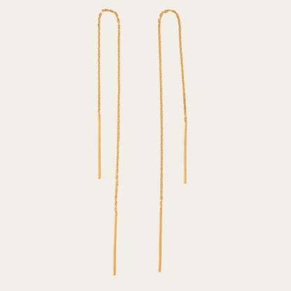 Two gold chain earrings on a beige background