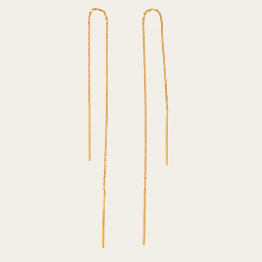 Two gold chain earrings on a beige background