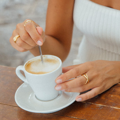 image of woman drinking coffee wearing gold rings