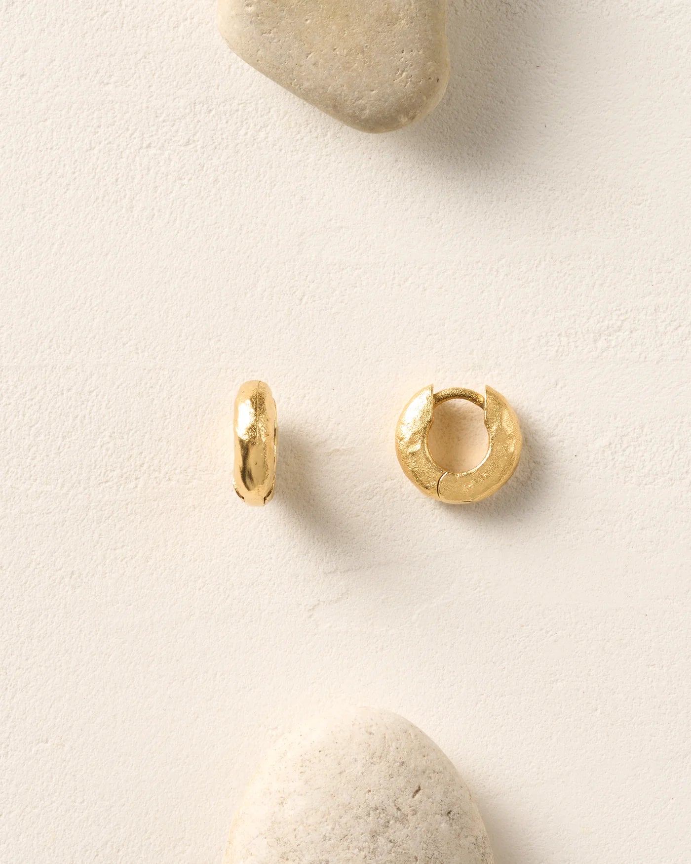 Gold hoop chunky earrings on white textured background