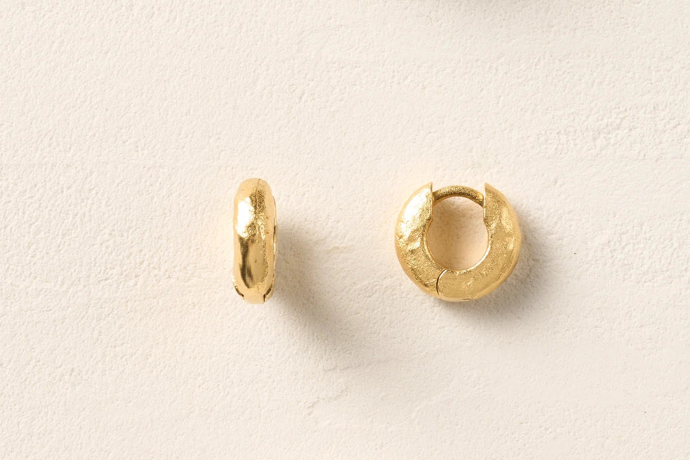 Gold hoop chunky earrings on white textured background