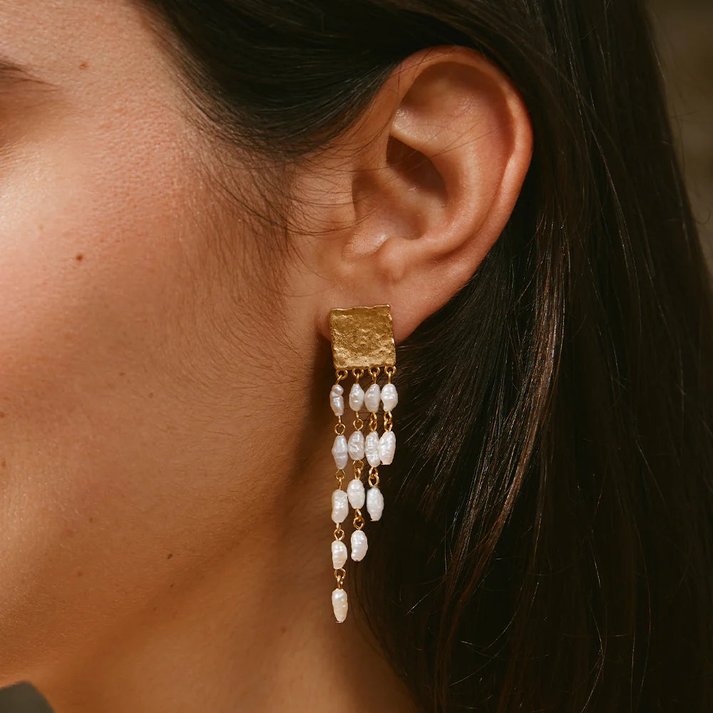 Gold earring with pearl drops worn by a person