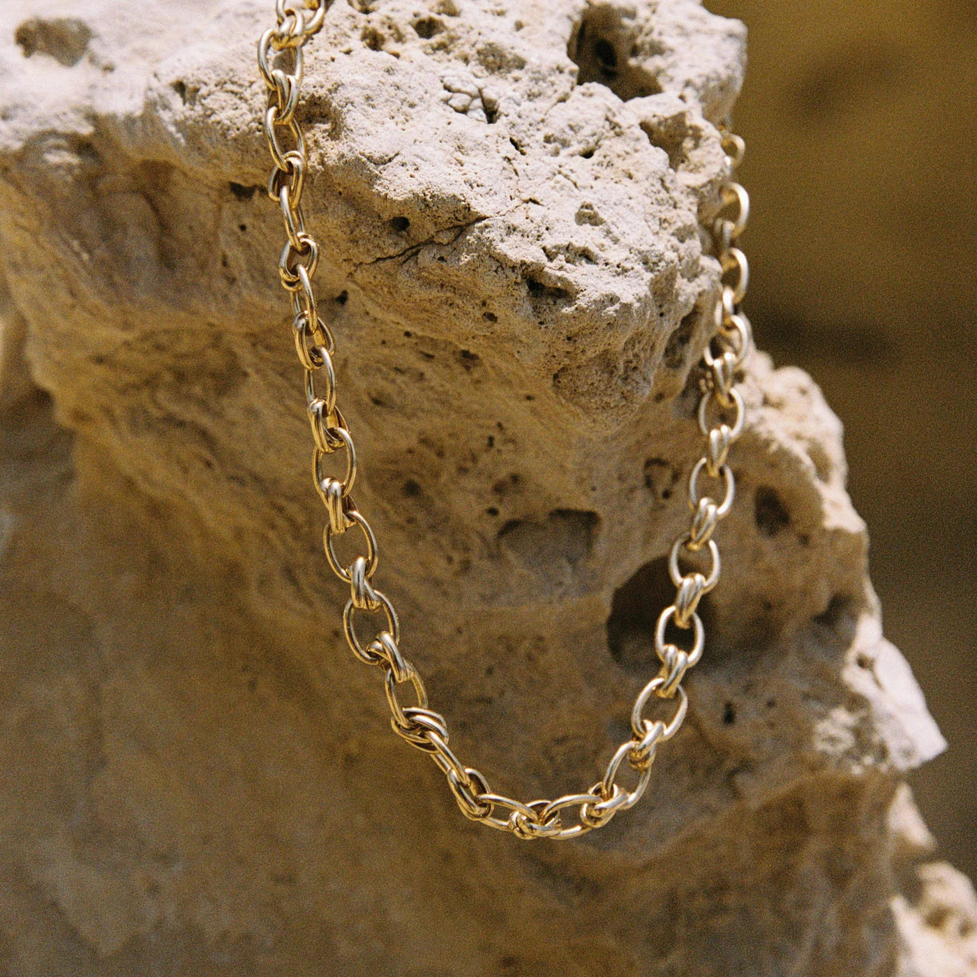 Gold chain draped over a textured stone surface