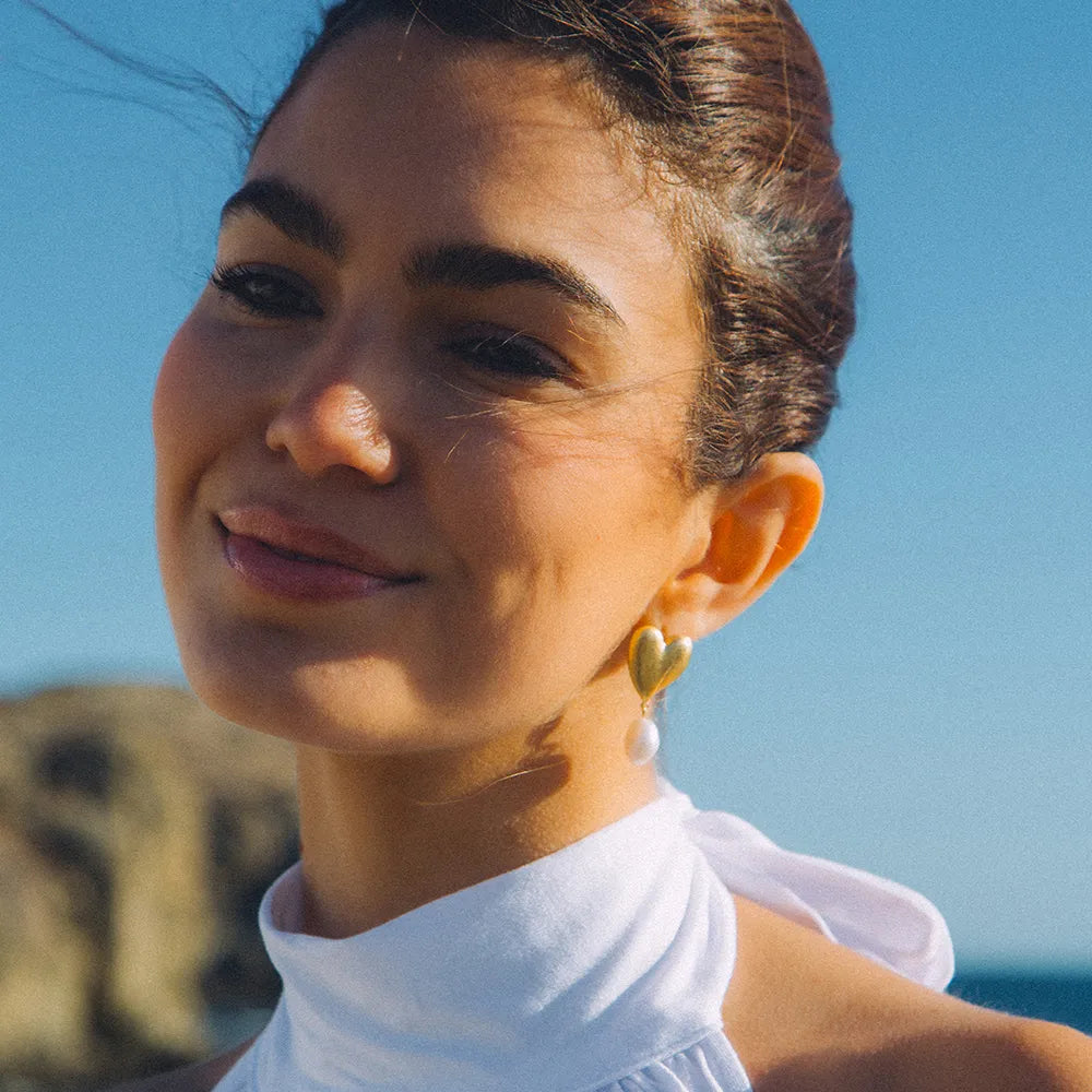 Woman wearing gold earrings with a clear blue sky background