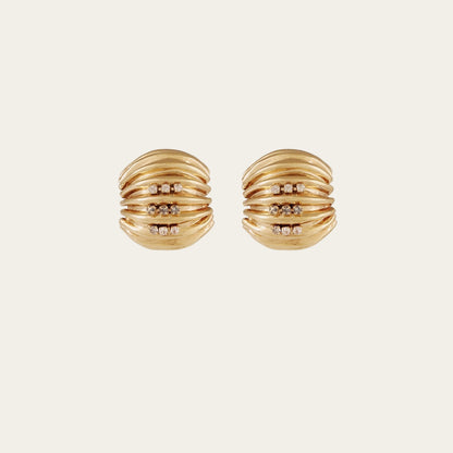 Pair of gold earrings with diamond accents on a light beige background