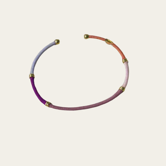 threaded coloured bangle with gold ends on flat lay surface