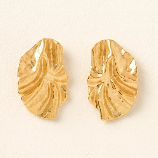 Gold leaf-shaped earrings on a beige background