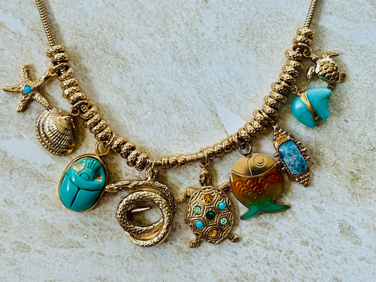 Necklace with various charms including a turtle, fish, and shell on a textured surface
