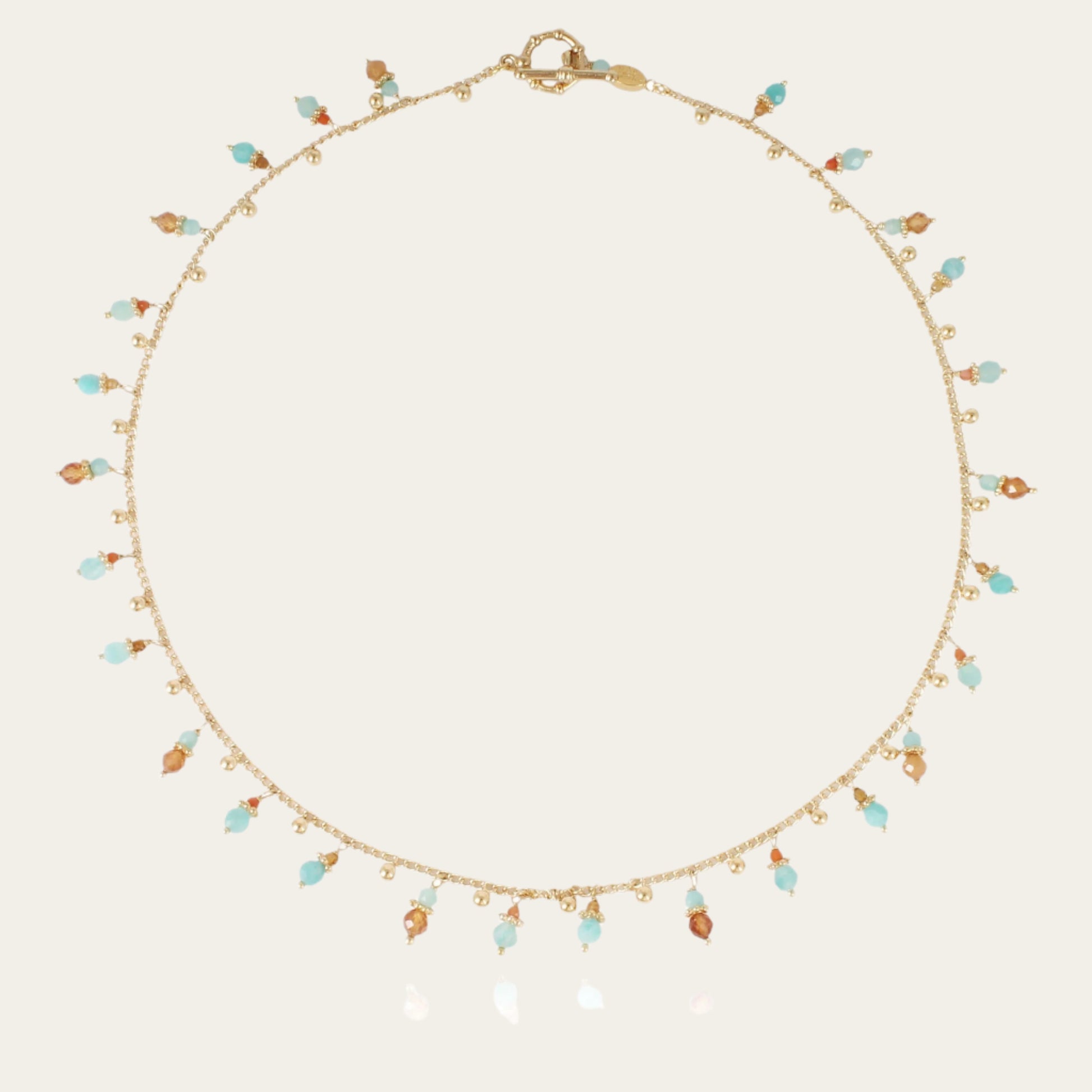 A gold-plated necklace with a series of tangerine-colored gemstone pendants and small pearls.