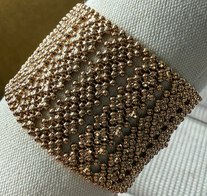 Close-up of a gold beaded bracelet on a white fabric background