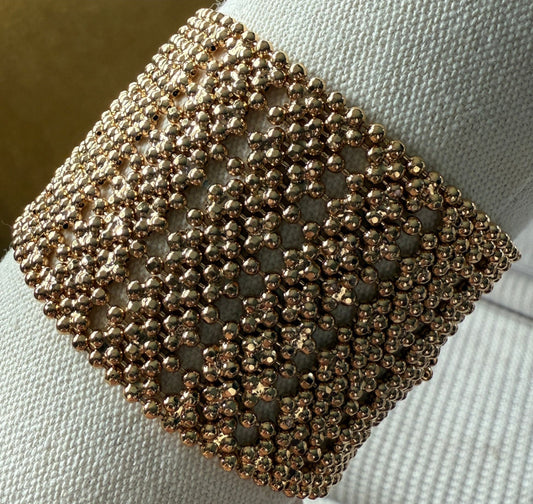 Close-up of a gold beaded bracelet on a white fabric background