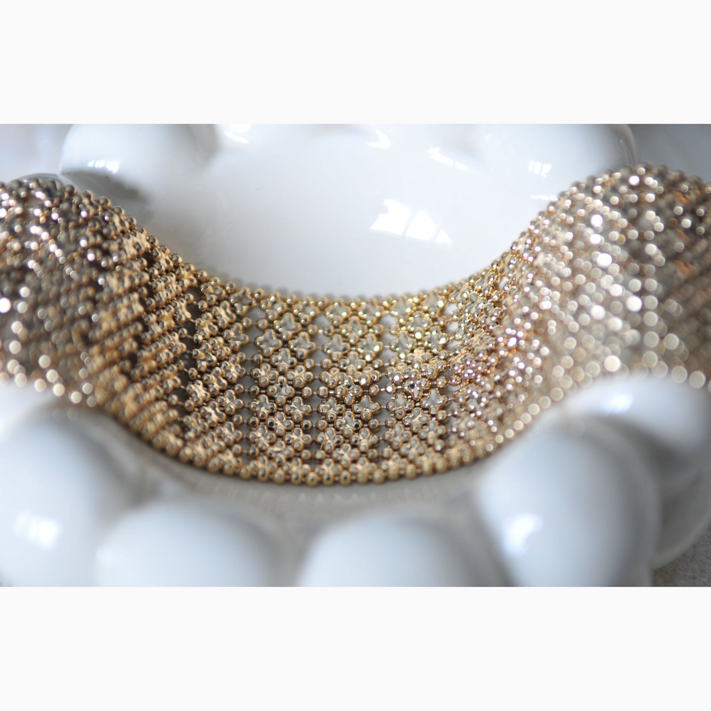 Gold beaded bracelet on a white surface