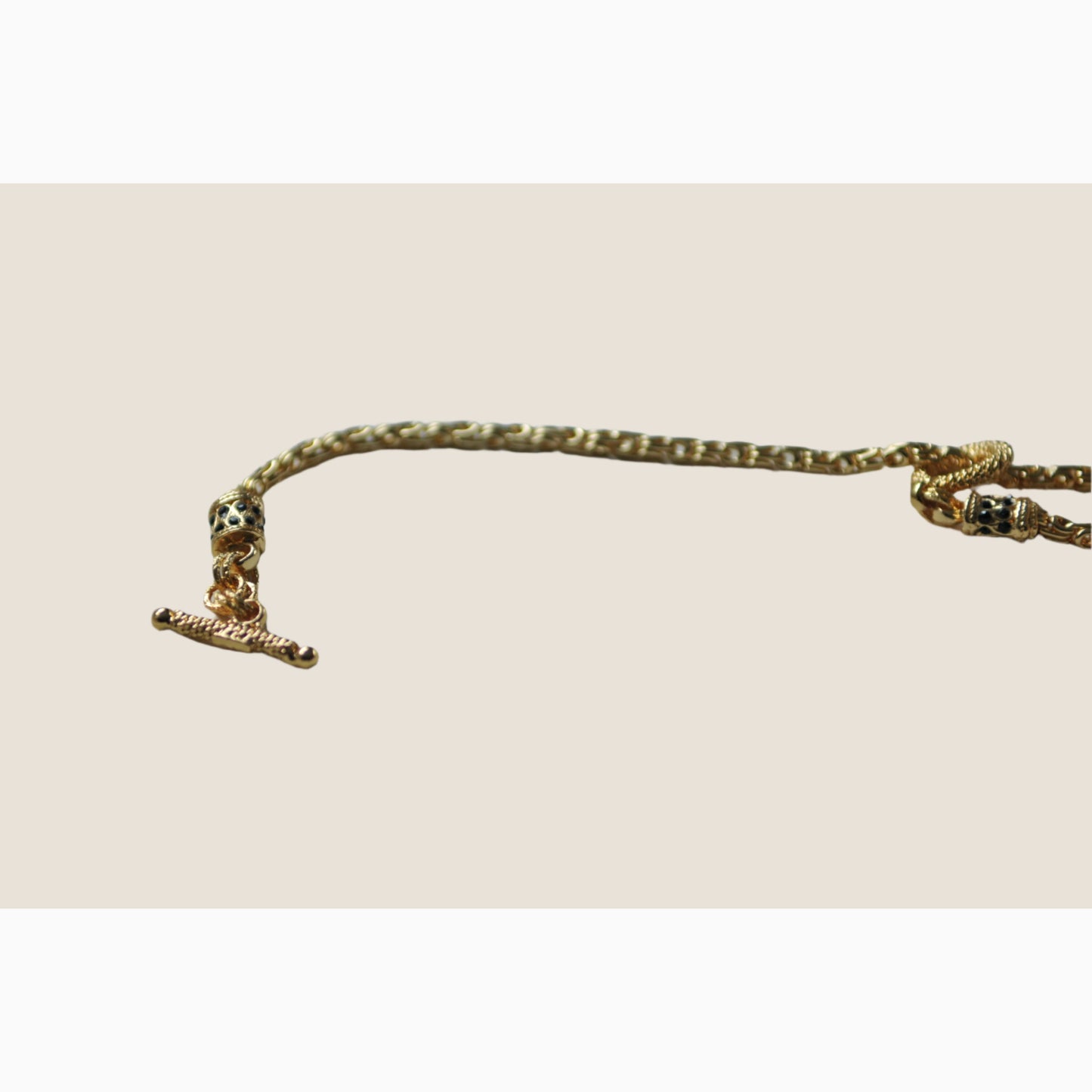 Gold anklet with a small charm on a light background
