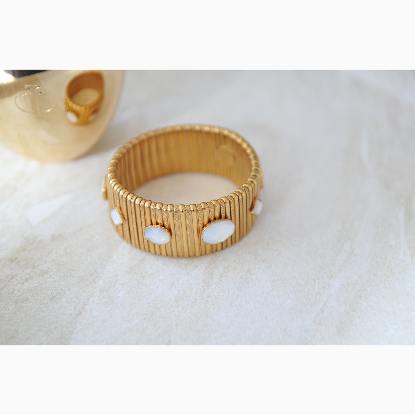 Gold bracelet with white stones on a light background
