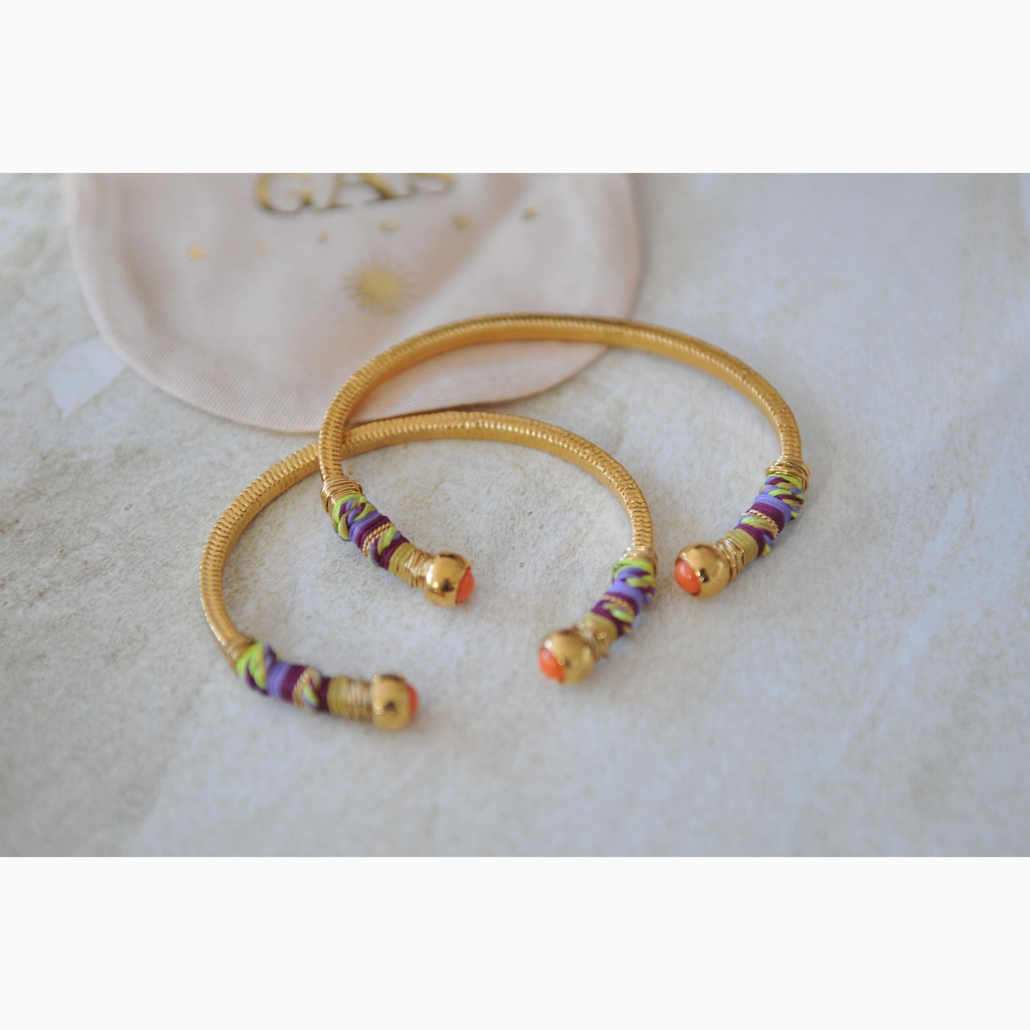 Gold bangles with colorful beads on a light background
