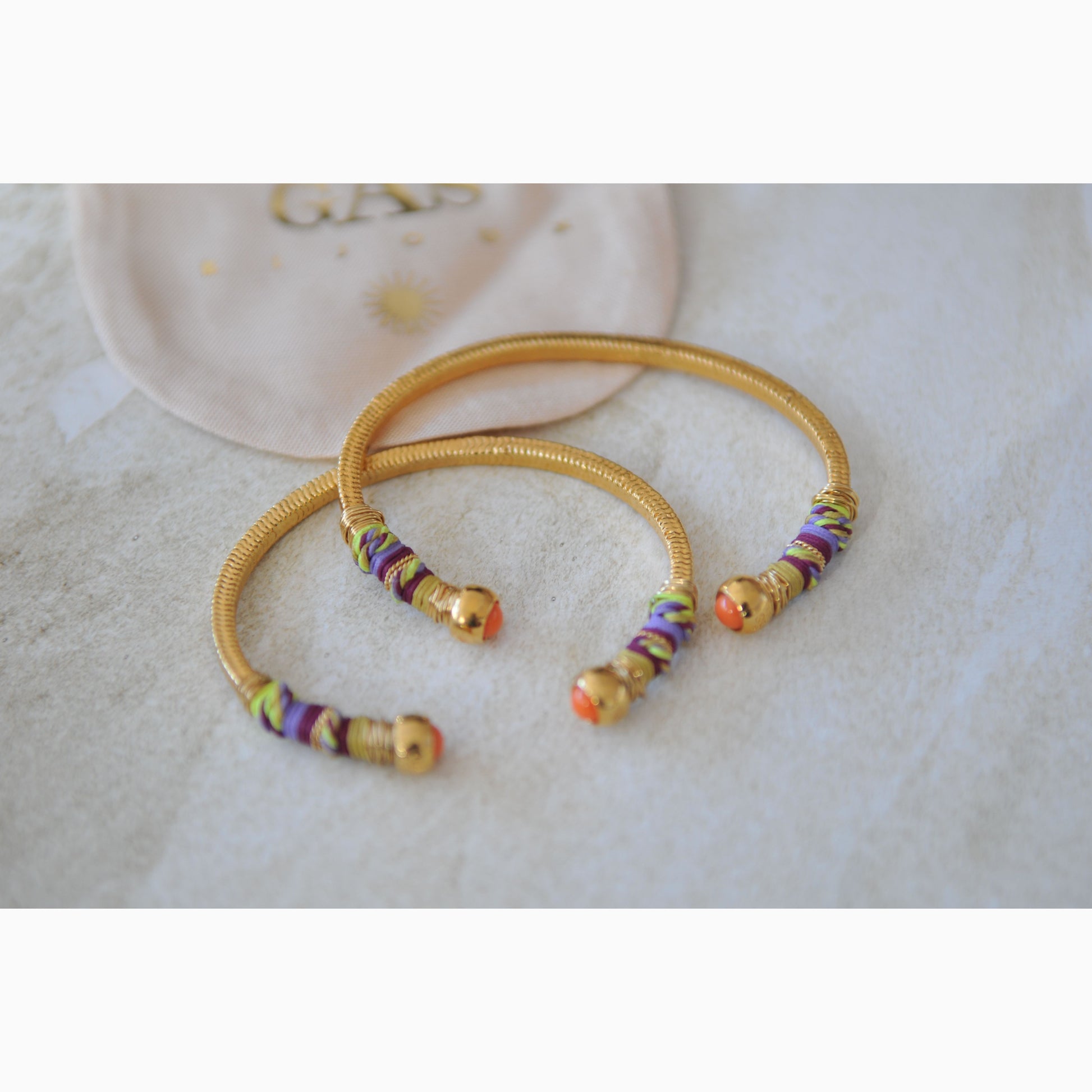 Gold bangles with colorful beads on a light background