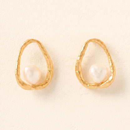 Gold earrings with pearl centers on a beige background