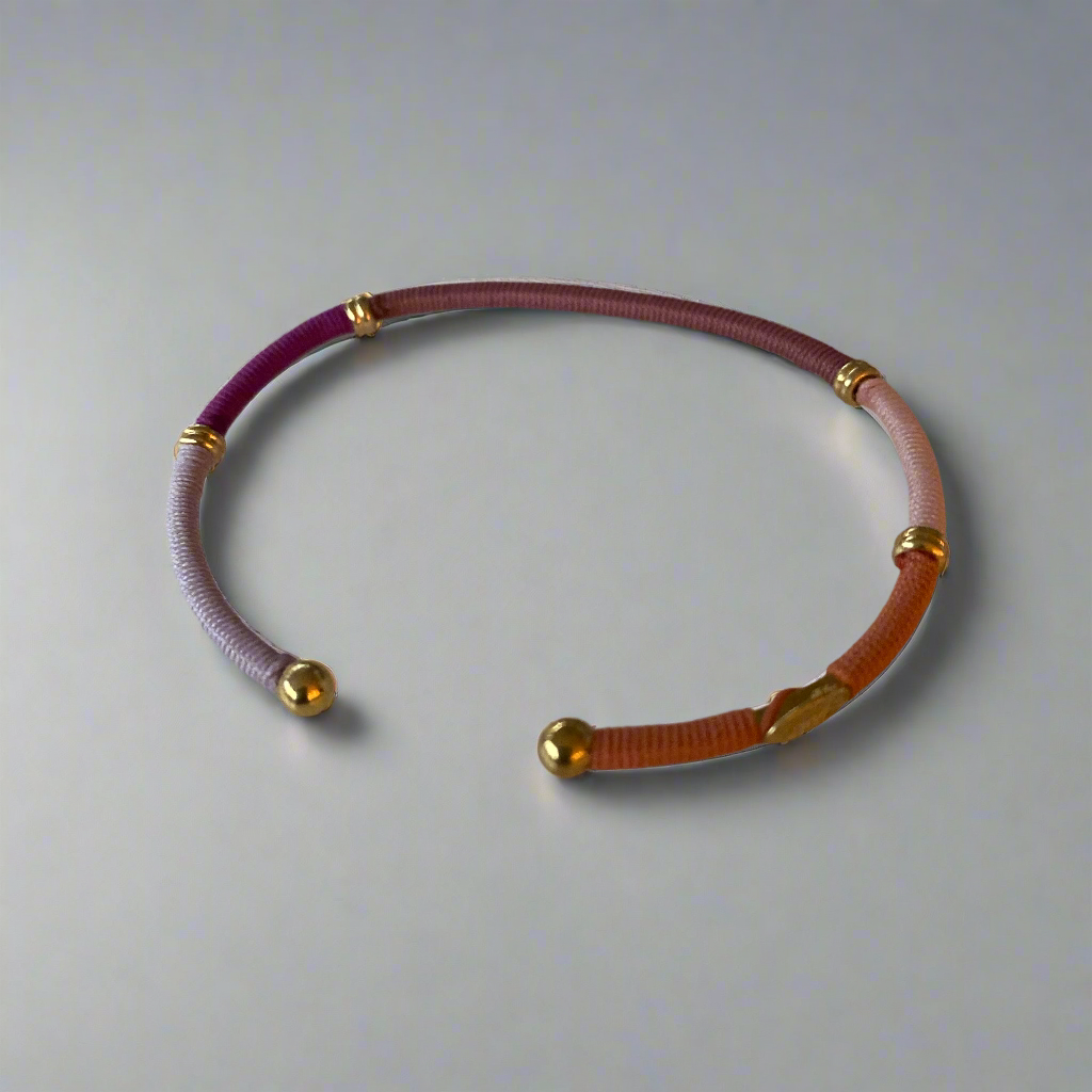 Coloured, threaded bangle on flat lay surface