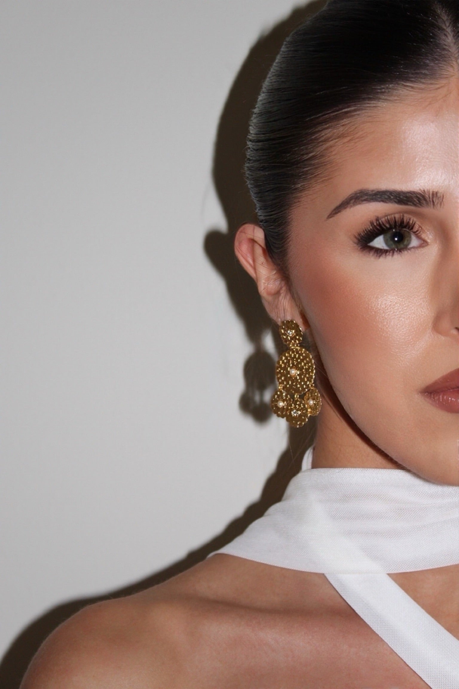 Woman wearing gold earrings with a neutral background