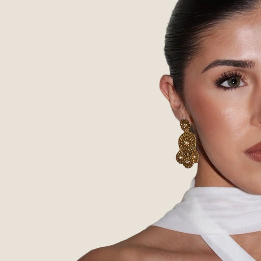 Woman wearing gold earrings with a neutral background