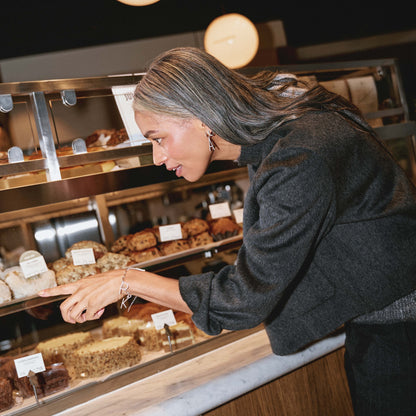 Woman selecting pastries from a bakery display case.