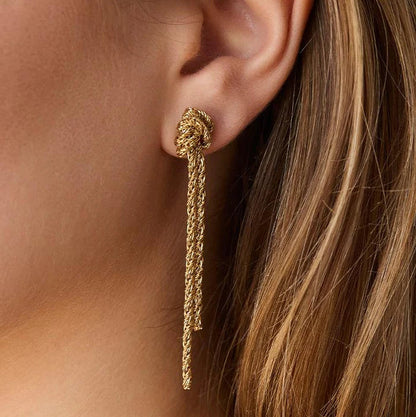 Gold earring worn by a person with blonde hair.