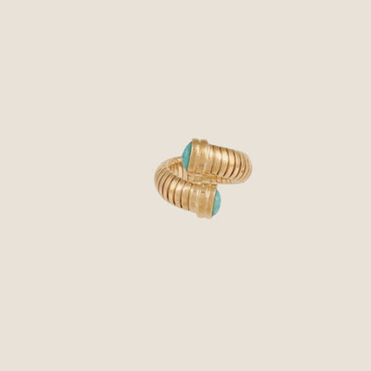 Gold plated ring with a flexible mesh design and turquoise gemstones, viewed from an angle on a white background