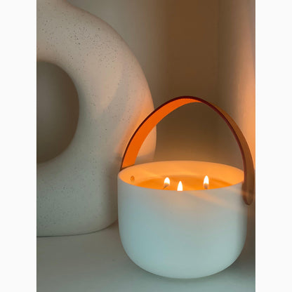 Ceramic candle lit with leather handle on shelf 