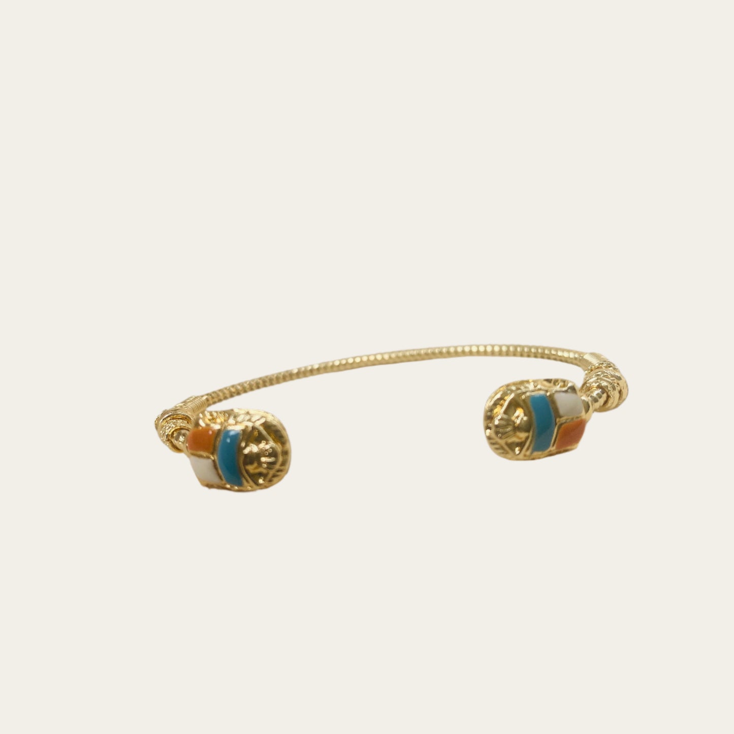 gold cuff with coloured stones on neutral background