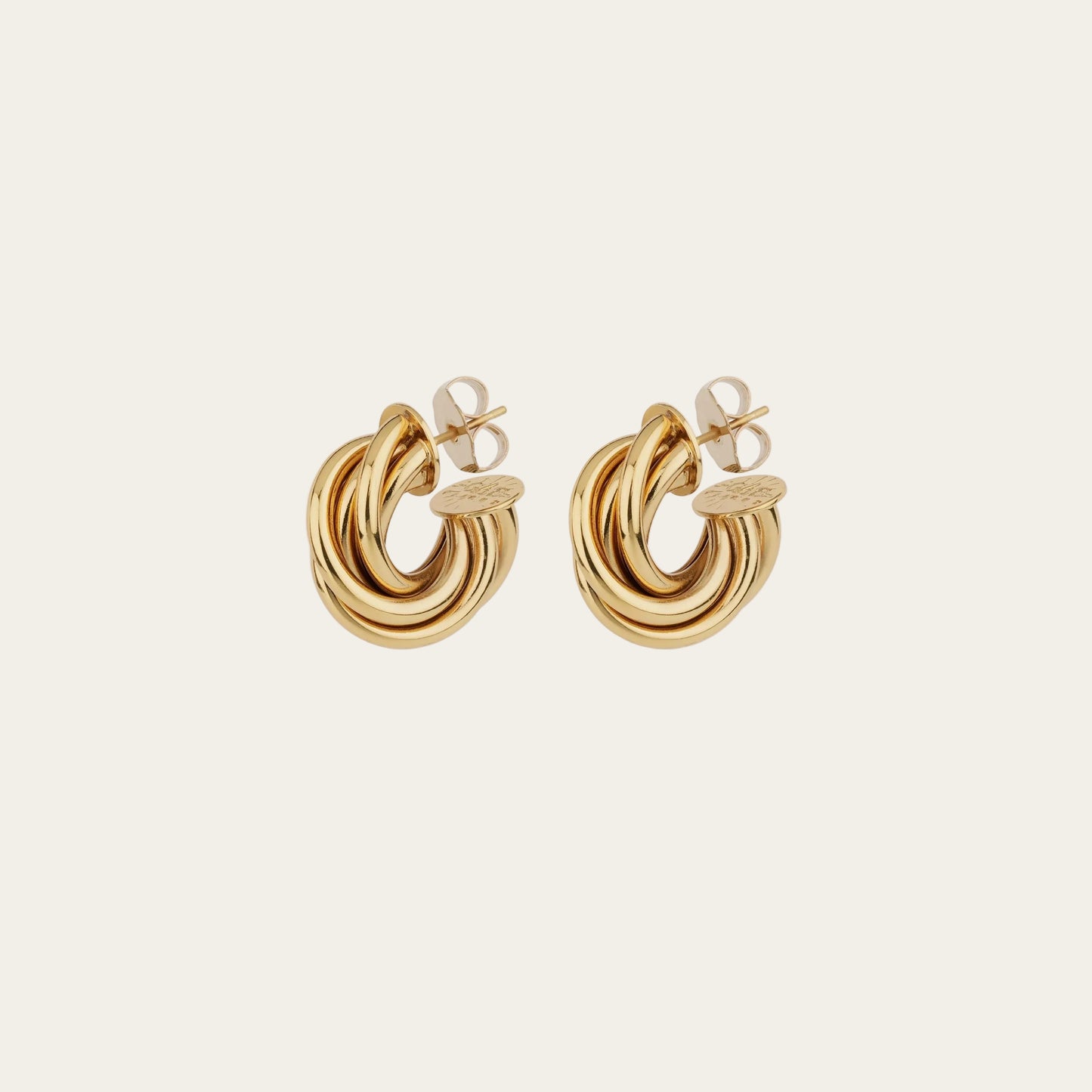 Gold hoop earrings on a light beige background