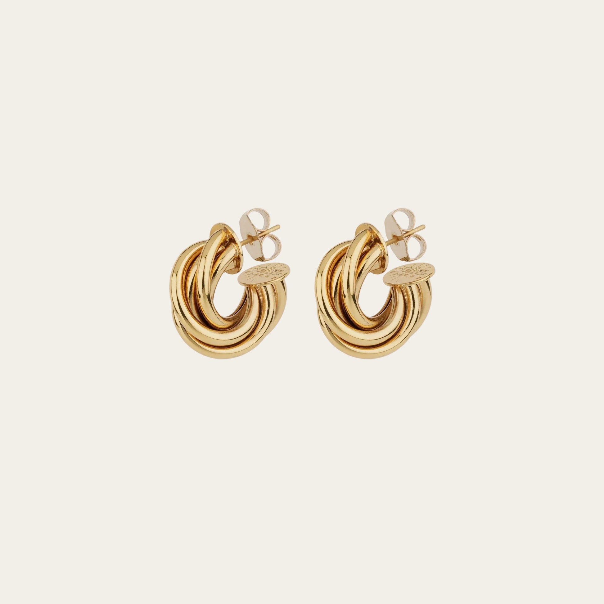 Gold hoop earrings on a light beige background