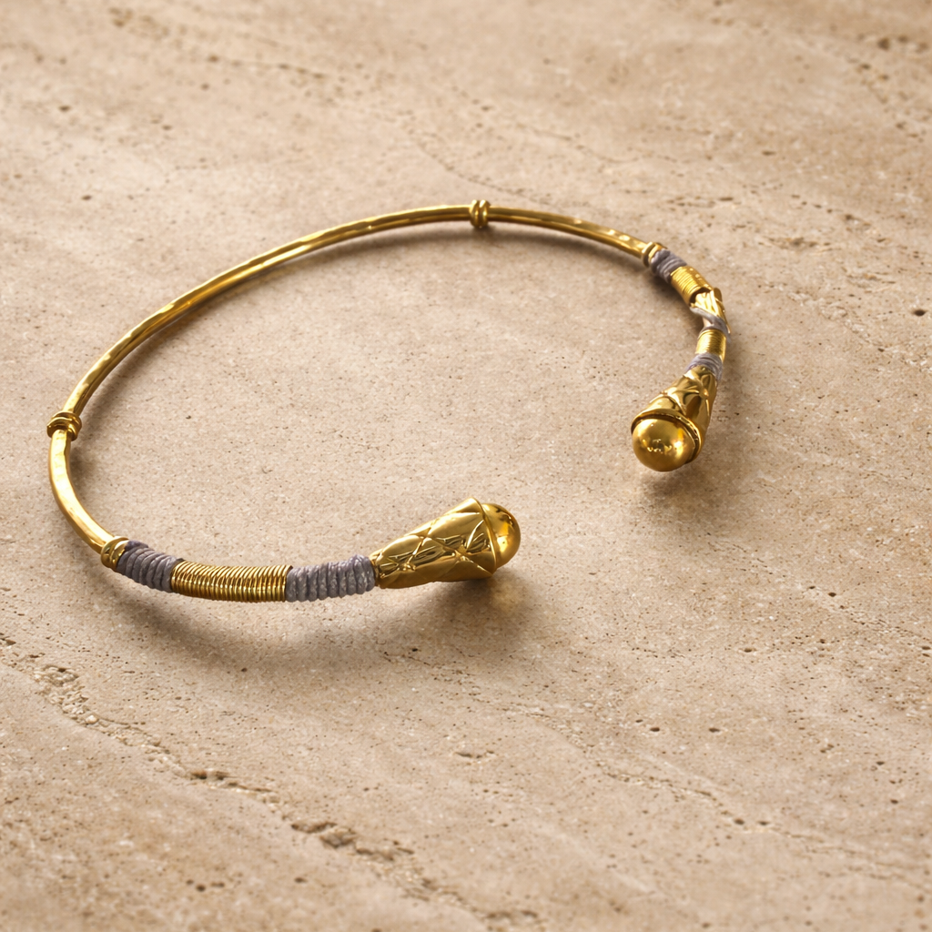 Gold bracelet with decorative elements on a beige surface